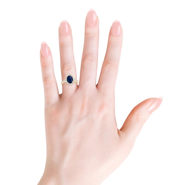 9x7mm A Classic Oval Blue Sapphire Halo Ring with Diamond Accents in Yellow Gold body-hand